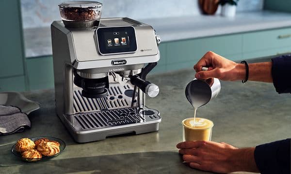 Henkilö tekee taiteellisen kuvion cafe latte -kahvijuoman pintaan