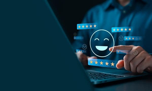 Person bruger en bærbar computer, og illustrerede femstjernede anmeldelser og en smiley