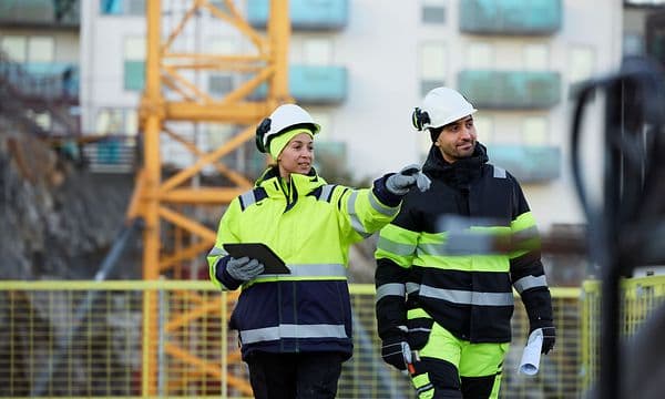 To bygningsarbejdere går på en byggeplads