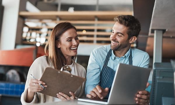 Mand og kvinde sidder ved et bord og arbejder på bærbar computer