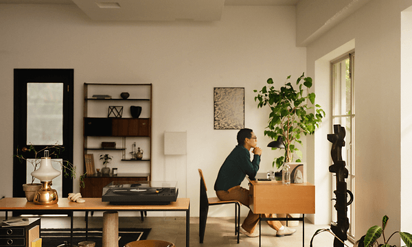 En person tittar ut genom fönstret medan han lyssnar på vinylskivor på Sony LX5BT-skivspelaren