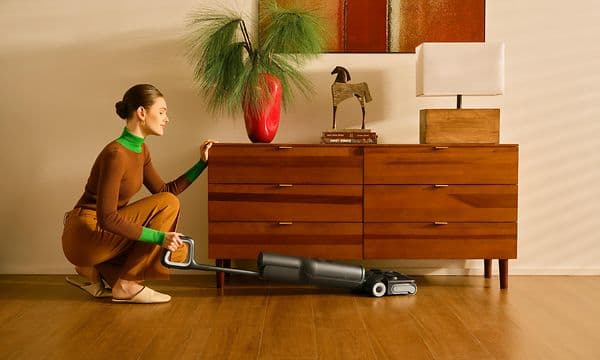Kvinde støvsuger under kommode med Roborock F25 ACE Combo
