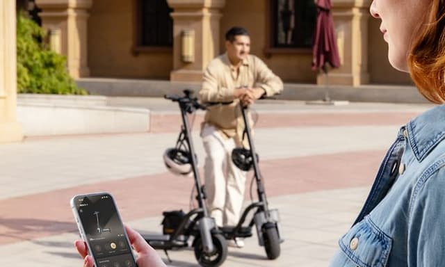 Kvinne kobler sparkesyklen til mobilapp