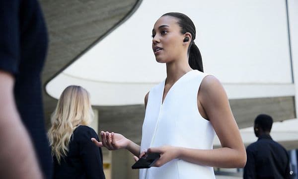 Kvinde står og snakker med høretelefoner i ørerne