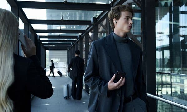 Mand med høretelefoner i ørerne omgivet af mennesker