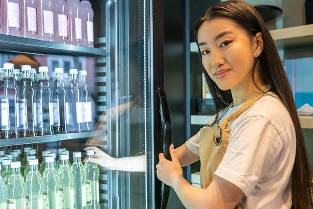 Kvinde sætter en flaske i køleskabet