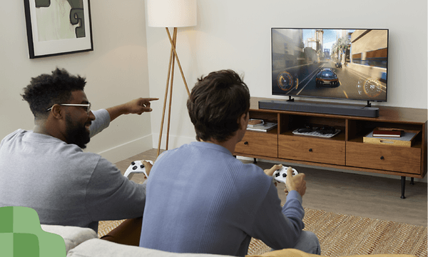 To personer spiller videospill i stue med lyd via JBL SB595-lydplanke