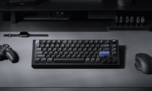 Tangentbord på ett skrivbord bredvid en handkontroll, en mus och en smartklocka