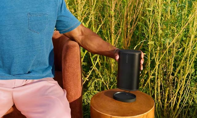 Man ställer ned svart Sonos Play-högtalare på laddstationen