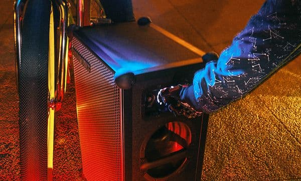 To personer står ved siden af en Soundboks 4-højttaler og en cykel med lys på