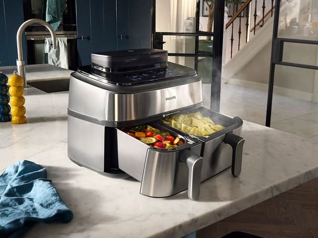 Philips Airfryer 5000 -kiertoilmakypsennin ja höyryävää ruokaa keittiön pöydällä