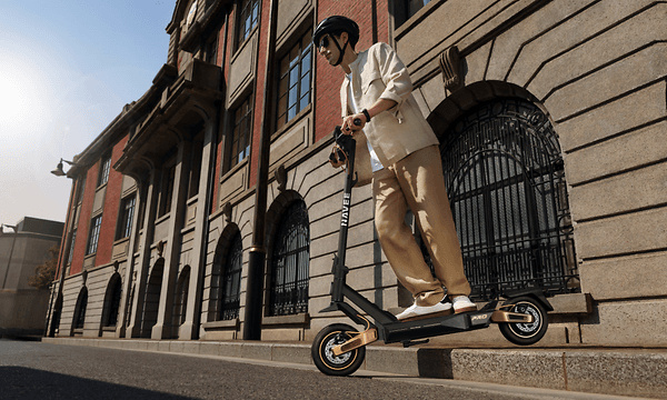 En mann trikser på fortauskant med sin Navee ST5 Pro elsparkesykkel