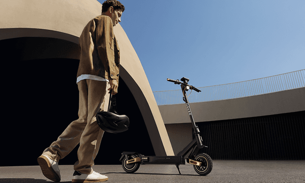 En mann går mot sin parkerte Navee ST5 Pro elsparkesykkel på en parkeringsplass