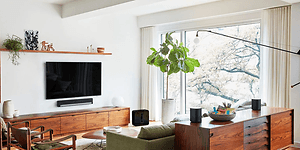 Modernt vardagsrum med platt-TV på väggen, soundbar under och flera smarta högtalare runt om i rummet.