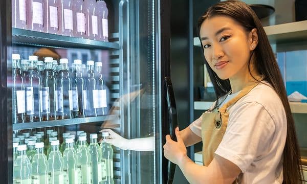 Woman grabbing a beverage from Frigelux professional refrigerators