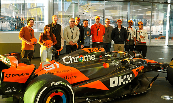 Joukko ihmisiä kuvassa kilpa-auton vieressä