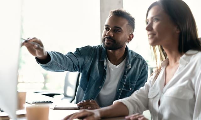 Mann og kvinne som jobber på en PC i kontoret