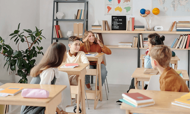 Airthings luftkvalitetsmätare på en klassrumshylla bakom eleverna