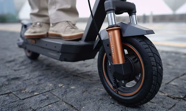Framdäck av en Navee GT5 Max elsparkcykel på en kullerstensgata