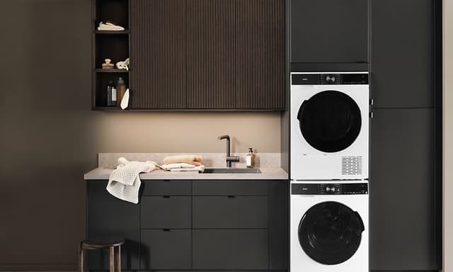 Kodinhoitohuone, jossa tummat Epoq-kaapistot integroidulla pesutornilla