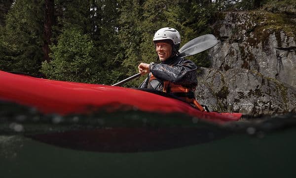 En kille paddlar kayak samtidigt som han pratar med sin smartklocka