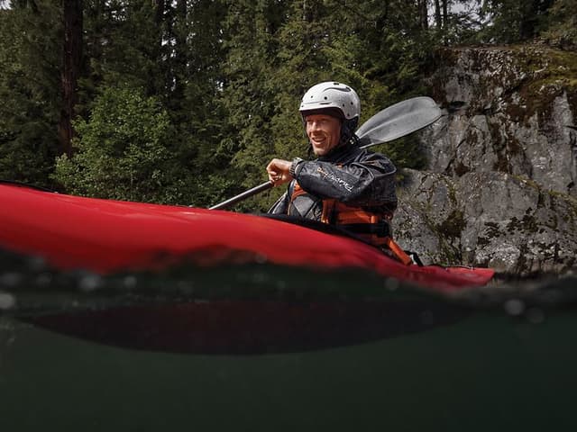 En kille paddlar kayak samtidigt som han pratar med sin smartklocka