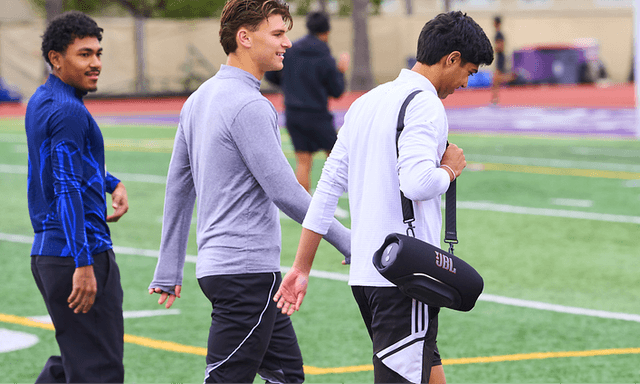 Fotbollsspelare bär JBL Xtreme 5 högtalare på sin axel med hjälp av axelremen som ingår