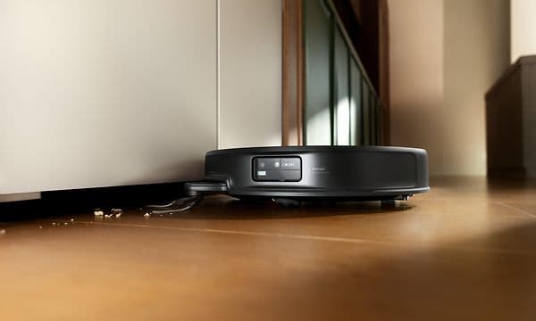 Roborock Saros 20 støvsuger smuler under et lavt møbel.