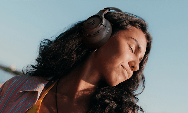 Kvinde med lukkede øjne, der har JBL Tune 785-høretelefonerne på