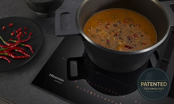 Padassa poreileva muhennos ja vieressä lautasellinen punaisia chilejä