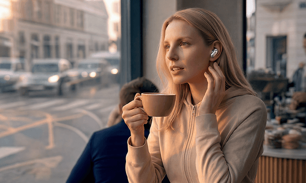 Nainen puhuu puhelua kahvilassa Soundcore Liberty 5 Pro -kuulokkeilla
