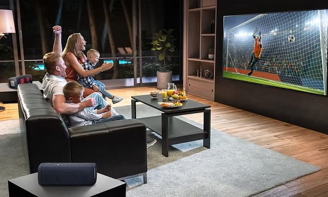 Foreldre og barn som lykkelig ser TV fra sofaen