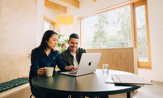 Elgiganten-anställd och kund som använder MacBook och arbetar med Apples affärslösning