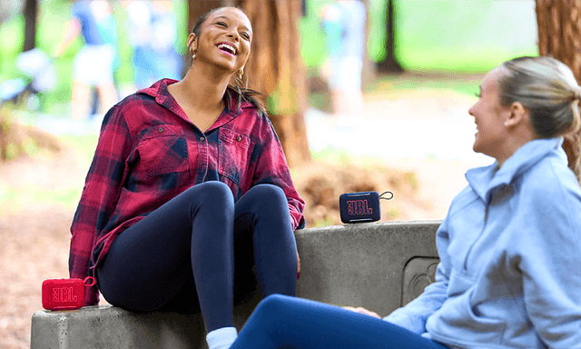 Kaksi naista kuuntelee musiikkia ulkona JBL GO5 -kaiuttimella