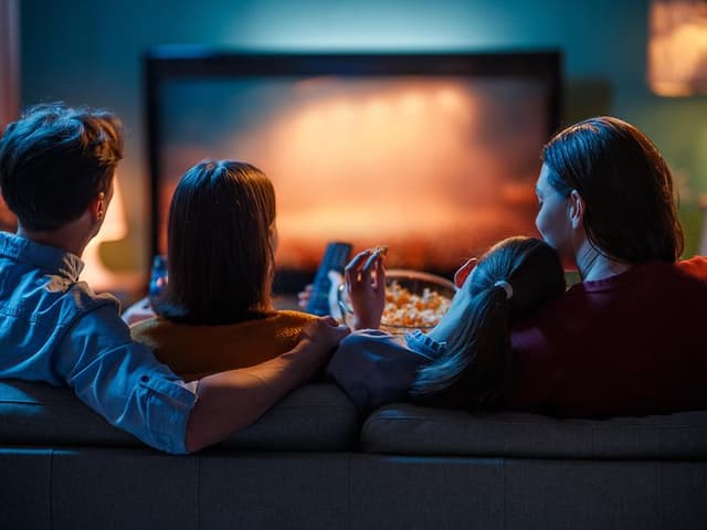 Fire personer sidder i en sofa og ser tv