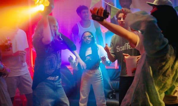 En pige holder Soundboks Lightboks over sit hoved, mens folk omkring hende danser
