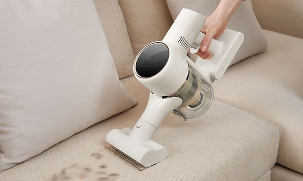 Person rengør en sofa med multibørsten