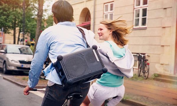 En man som cyklar bredvid en kvinna med Soundboks Rider högtalare på ryggen.