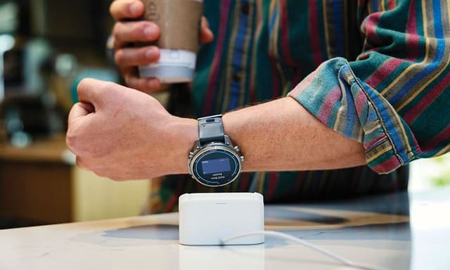 En mann som betaler for en takeaway-kaffe med Garmin Pay på en kafe.