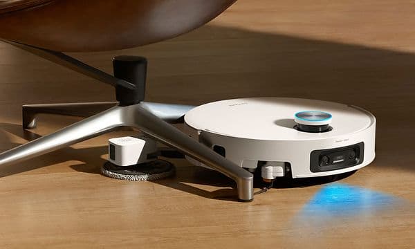 Dreame X60 Pro Ultra rengjør mens den navigerer rundt en stol ved hjelp av UltraExtend-armene.