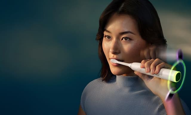 En kvinne som pusser tennene med Philips Sonicare DiamondClean elektriske tannbørste.