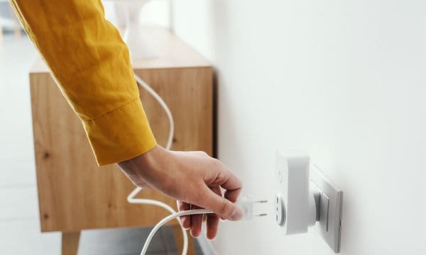 Henkilö kytkee laitteen älykkääseen Wi-Fi-pistorasiaan