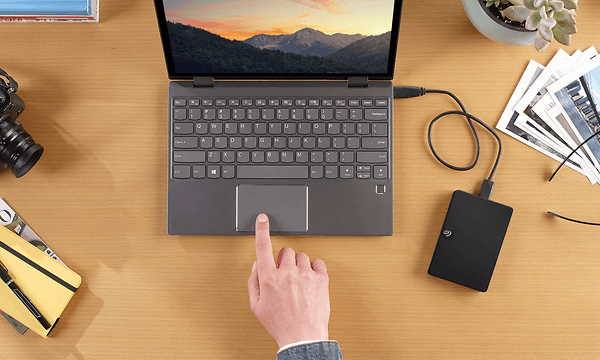 Mies siirtää tiedostoja läppäriltä Seagate Expansion Plus -kannettavalle kovalevylle