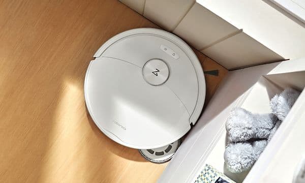 Hvit Roborock Qrevo 2 Pro som rengjør gulvet i et hjørne.