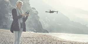 Kvinne på strand flyr drone