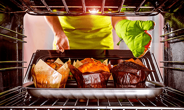 person tar ut muffins av ovnen
