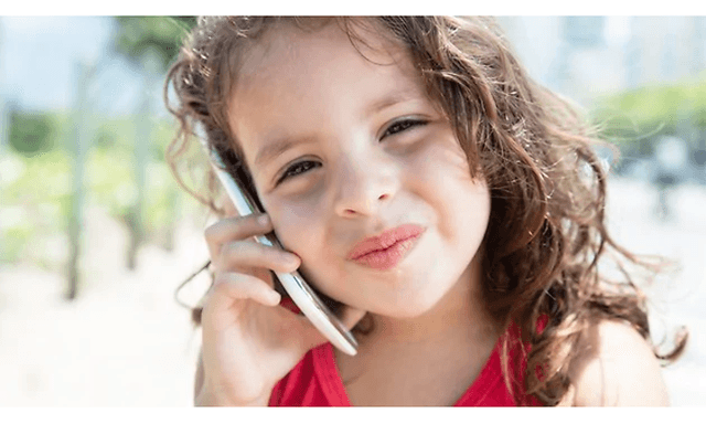 En ung flicka gör ett nöjt ansikte medan hon pratar i sin mobiltelefon.