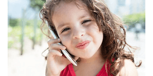 En ung flicka gör ett nöjt ansikte medan hon pratar i sin mobiltelefon.
