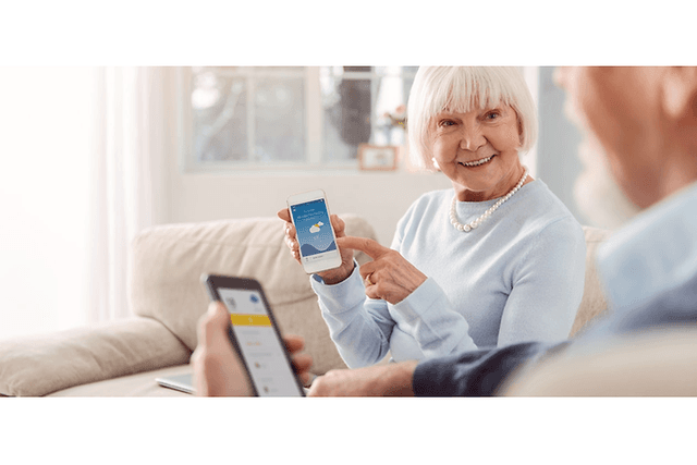 Ældre dame med hendes smartphone der smiler