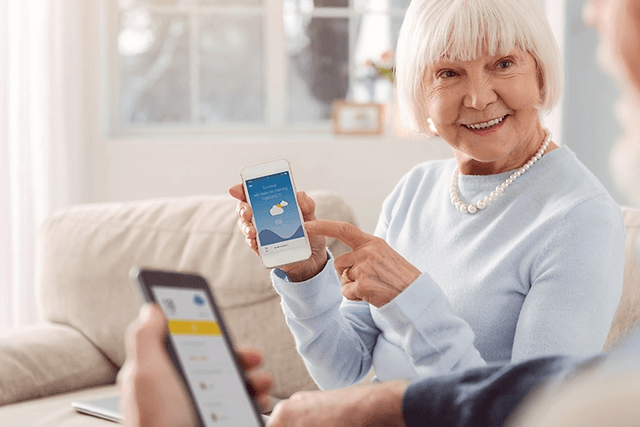 Ett äldre par visar varandra något på sina smartphones.